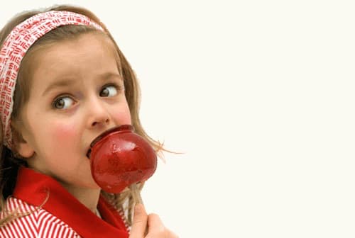 Young Girl Eating a Homemade Red Candy Apple