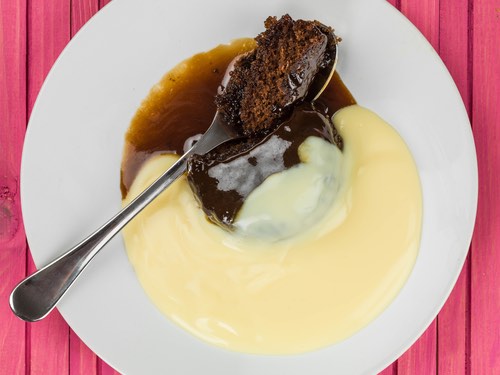 Sticky Toffee Pudding Served with Custard Sauce on a Plate