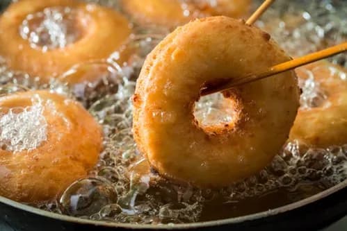 Turning Donuts with Wooden Skewers During Frying